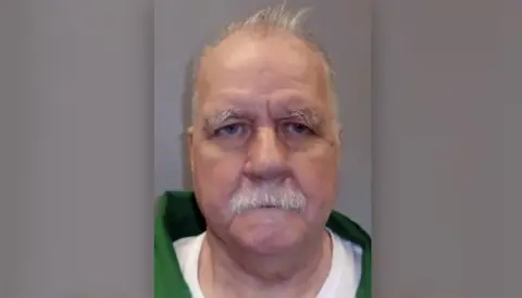 South Carolina Department of Corrections Brad Sigmon, a white man with a grey mustache, wears a green jumpsuit and appears in a mugshot